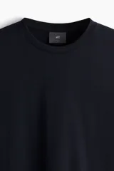 Remera negra de corte ajustado en punto suave de algodón pima, con cuello redondo ribeteado acanalado fino y bajo recto.