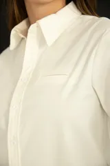 Camisa blanca de corte clásico con bolsillo en el pecho, mangas largas y botones al tono.