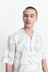 Camisa de manga corta con cuello pijama y estampado abstracto en tonos celeste, beige y blanco.