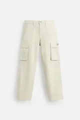 Pantalón cargo color beige, de corte relaxed fit, confeccionado en tejido de algodón con elasticidad. Cuenta con bolsillos frontales, traseros y bolsillos tipo parche con solapa en las perneras. Tiene efecto lavado y cierre frontal con cremallera y botón.