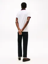 Chomba blanca de algodón elástico con cuello tejido azul marino y ribetes rojos. Logo de Tommy Hilfiger bordado en el pecho.