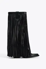 Bota de cuero negra estilo cowboy, con punta fina, taco de 7,5 cm y detalle de flecos en el cuerpo.