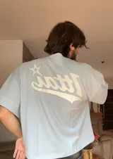 Remera negra de corte holgado con estampado en la espalda con la palabra "Ittai" en blanco y una estrella.