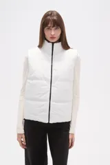 Chaleco acolchado blanco, sin mangas, con cuello alto y cierre frontal negro.