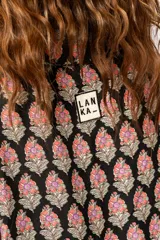 Conjunto de camisa y short negro con estampado de flores rosas. La camisa es de corte holgado con tajos laterales.