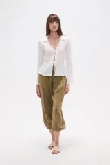 Blusa blanca de algodón con textura fruncida, manga larga y escote en V con lazo ajustable en el centro del busto.