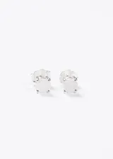 Par de aros tipo botón (studs) de plata 925, con engaste de cuatro garras y piedra redonda de color blanco lechoso, probablemente piedra luna.