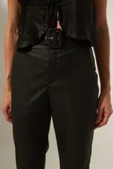 Pantalón negro de ecocuero, corte recto, tiro alto y cinturón con hebilla cuadrada.