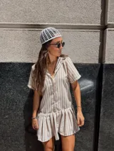 Vestido camisero corto de algodón con rayas verticales color beige y blanco, cuello camisero, cierre frontal con botones y falda con volado.