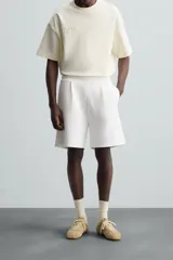 Bermuda color arena de tejido interlock de algodón con elasticidad, corte relaxed fit, cintura elástica ajustable con cordón interior, bolsillos laterales y bolsillo trasero de plastrón.