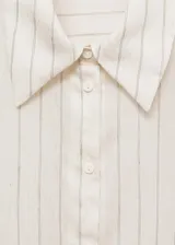 Camisa celeste con rayas verticales finas, de tejido fluido, manga larga abotonada, cuello camisero y corte recto.