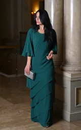 Vestido largo de fiesta color verde oscuro, con mangas acampanadas y falda con volados en cascada. Incluye clutch plateado.