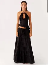 Conjunto negro con top de cuello halter y volantes y pollera larga y fluida tiro bajo.