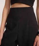 Pantalón de vestir negro, de corte palazzo, sin cintura, con pliegues y cierre trasero.