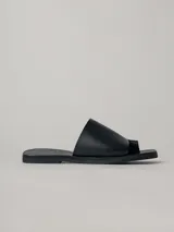 Sandalias planas de cuero color negro, con tira ancha sobre el empeine y tira entre los dedos. Suela plana de goma.