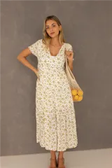 Vestido largo blanco con estampado de flores amarillas, escote en V, mangas cortas y falda con volantes. Tiene aberturas laterales en la parte inferior y forro interior.