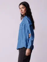 Camisa celeste de lyocell, marca Zac & Rachel. Cuello con solapa, abertura central con botones y bolsillos delanteros.