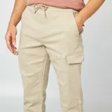 Pantalón cargo color beige, de corte slim fit, con cintura ajustable con cordón, bolsillos laterales con solapa y puños elásticos.