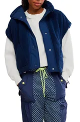 Chaleco de piel sintética tipo sherpa en color azul marino, con cuello alto y cierre frontal de broches a presión. Presenta un diseño de hombros caídos y corte holgado.