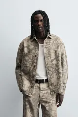 Sobrecamisa color beige con estampado abstracto en tonos grises, de corte relaxed fit, cuello solapa, manga larga con puños abotonados, bolsillos de plastrón en el pecho, efecto lavado y cierre frontal con botones.