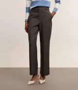 Pantalón de vestir gris claro, de corte recto, con bolsillos laterales y traseros. Se ajusta a la cintura con cinturón de cuero negro.