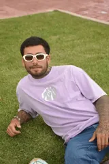 Remera color beige de algodón premium, manga corta y cuello redondo. Presenta un estampado circular en el centro del pecho con un diseño abstracto en tonos grises.