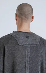 Sweater gris oscuro de corte recto, cuello redondo y mangas largas con detalle de costuras a los lados.