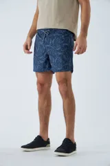 Short de baño azul con estampado de hojas y flores en blanco. Tiene cintura elástica con cordón ajustable, dos bolsillos laterales y uno trasero.