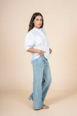 Blusa blanca con detalles bordados en toda la superficie, cuello levemente subido y botones al frente.