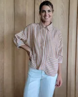 Camisa color beige con rayas verticales blancas, cuello clásico, mangas 3/4 y bolsillos frontales cuadrados.