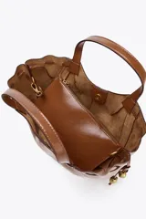 Bolso de mano color marrón con detalle de pespuntes en el cuerpo y tiradores laterales con abalorios en efecto metalizado. Tiene doble asa de mano y correa extraíble para usar como bandolera. Incluye cartera interior con cierre de cremallera y cierre imantado.