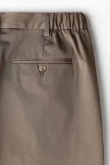 Short color marrón claro, de corte recto y largo a la rodilla. Presenta cintura con elástico en los laterales, cierre con botón, bolsillos al bies y bolsillos traseros ribeteados con botón.