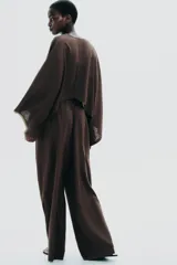 Pantalón blanco de lino, de corte ancho y tiro medio, con cintura elástica ajustable con cordones y bolsillos laterales.