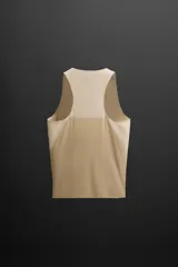 Musculosa deportiva color beige de tejido técnico ligero y elástico con estructura perforada. Tiene cuello redondo amplio, manga sisa con acabados termofijados, bajo con aberturas laterales y logo estampado.