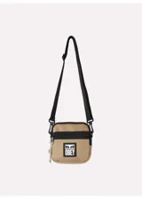Bolso bandolera pequeño color arena con detalles en negro y logo de Obey estampado en blanco. Tiene correa ajustable y cierre de cremallera.