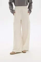 Pantalón de poliéster color crudo, de calce alto y corte palazzo con bolsillos laterales.