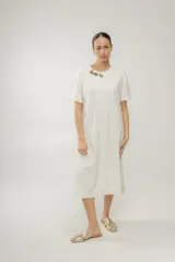 Vestido midi color crudo, corte recto, con cuello redondo, mangas cortas y detalle de apliques florales en el hombro.