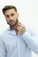 Camisa celeste de lino y algodón, de manga larga, corte semi slim y logo bordado.