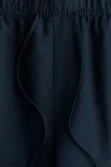 Pantalón tobillero azul marino de corte holgado en tejido liviano de mezcla de lino. Modelo de tiro alto con elástico revestido y cordón para ajustar fino en la cintura, bolsillos al bies y piernas ajustadas.
