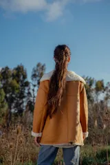 Campera gamulan color camel de cuero italiano con interior de piel sintética blanca. Tiene cuello solapa amplio, cierre con botones y bolsillos laterales.