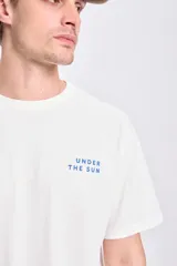 Remera de manga corta color crudo, corte oversize, con estampa de un sol y la frase 'The sun's rays light up the day' en la espalda.