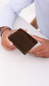 Billetera de cuero color marrón oscuro con volante interior, visor y tarjeteros. Cuenta con doble compartimento para billetes.