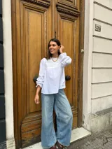 Camisa blanca de mangas largas con detalles de puntilla en el frente y en los puños.