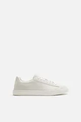 Zapatilla blanca de cordones fabricada en tejido transpirable de punto.