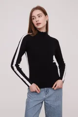 Sweater negro de punto con cierre de cremallera en el cuello y dos líneas blancas verticales en las mangas.