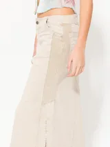 Pollera midi color beige con recortes en combinación de tejido en laterales, recortes en frente y espalda; y tajos en los laterales.