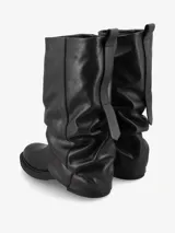 Bota de caña media de cuero negro suave, con diseño fruncido y silueta relajada. Presenta una base baja con suela resistente.