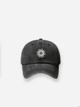 Gorro de gabardina negro con bordado frontal de un sol blanco.