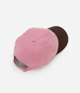 Gorra rosa con visera marrón, confeccionada en sarga de algodón, con bordado frontal con la frase "Just a Girl" en color marrón.