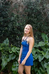 Vestido corto azul con escote halter y espalda descubierta. Presenta detalles de encaje negro en el escote y los laterales.